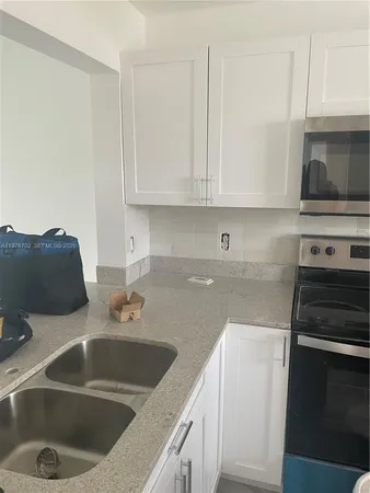 a kitchen with stainless steel appliances granite countertop a sink a stove and white cabinets