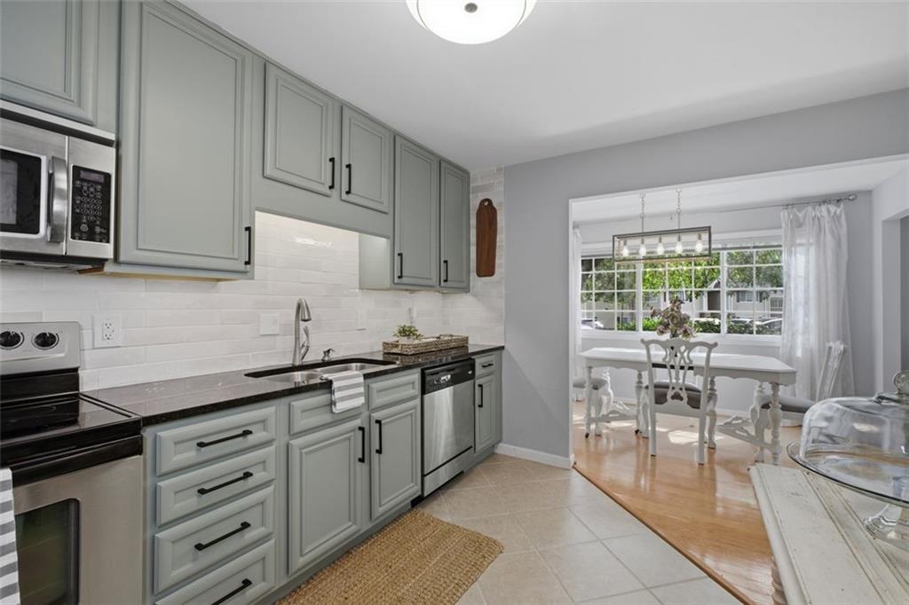 1468 Briarwood Road Northeast, Unit 901 Atlanta, GA 30319 - Photo 11 of 27 a kitchen with stainless steel appliances granite countertop a stove top oven a sink a dining table and chairs with white cabinets