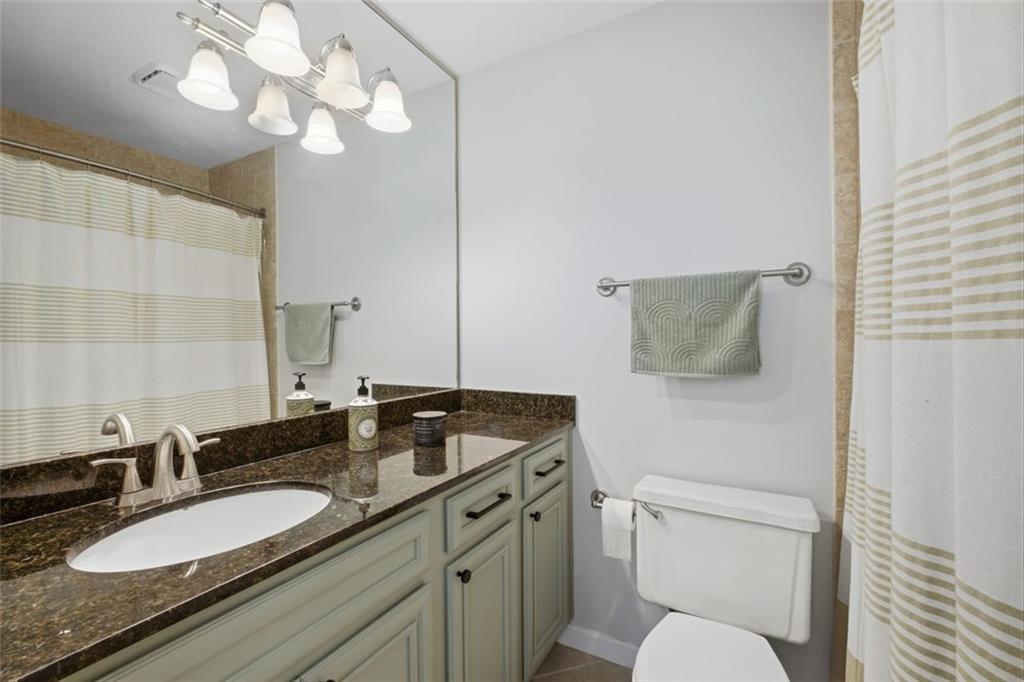 1468 Briarwood Road Northeast, Unit 901 Atlanta, GA 30319 - Photo 19 of 27 a bathroom with a granite countertop sink a toilet and a mirror