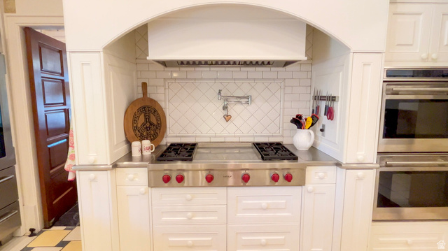 426 West Center Street Parowan, UT 84761 - Photo 15 of 107 Kitchen featuring a stainless steel range with red knobs, integrated double ovens, white cabinetry, subway tile backsplash, and a wall-mounted pot filler
