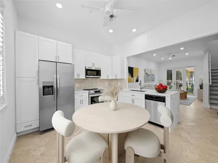 a kitchen with stainless steel appliances a dining table chairs refrigerator and sink