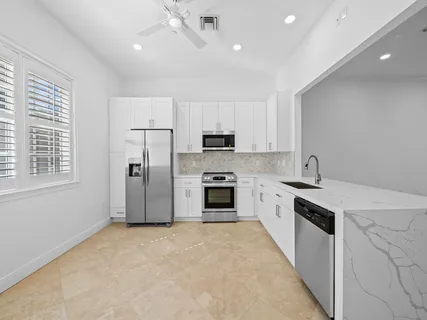 a large kitchen with stainless steel appliances granite countertop a stove a sink and a refrigerator