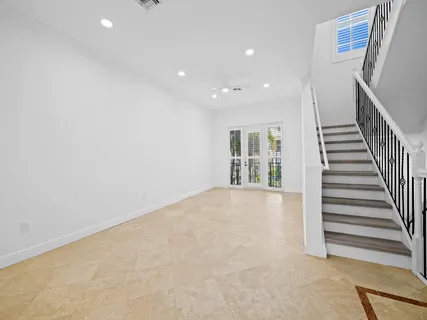a view of an empty room with wooden floor and stairs