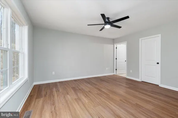 a view of empty room with wooden floor and fan