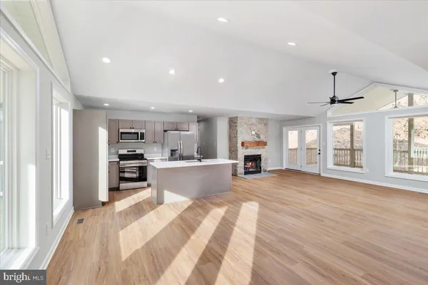 a large white kitchen with kitchen island a large window a sink and stainless steel appliances