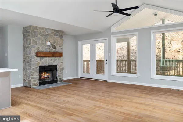 a view of an empty room with wooden floor fireplace and a window