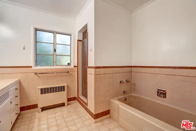 a bathroom with a tub a window and a glass door shower