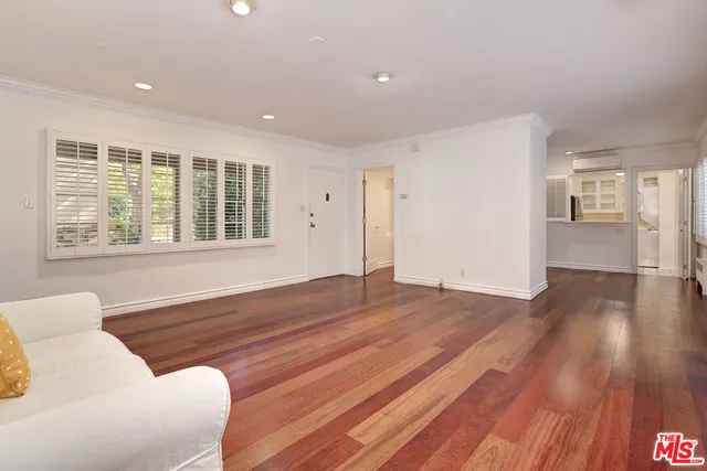 a view of an empty room with wooden floor and windows