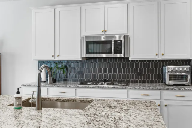 a kitchen with stainless steel appliances granite countertop a stove a microwave and a sink