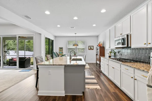 a large kitchen with stainless steel appliances kitchen island granite countertop a large window and a sink