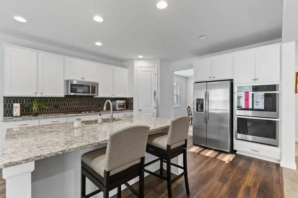 a kitchen with stainless steel appliances granite countertop a refrigerator a stove a sink a dining table and chairs