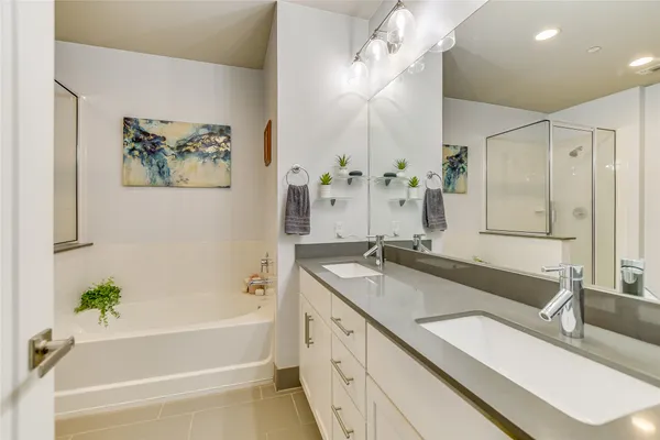 a bathroom with a granite countertop sink a large mirror and a bathtub with shower