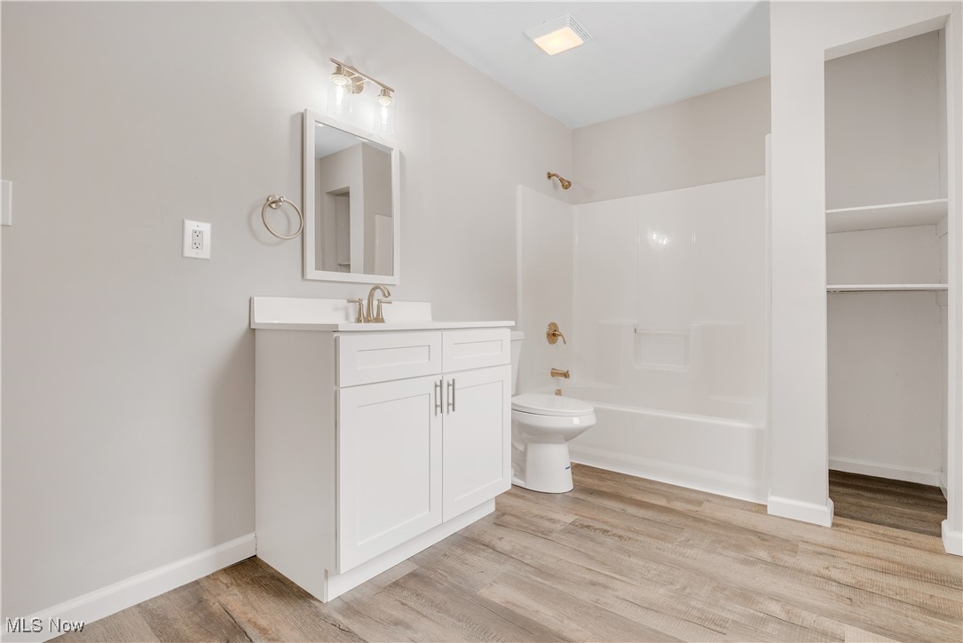 1893 Benjamin Road Madison, OH 44057 - Photo 7 of 23 Bathroom featuring toilet, wood finished floors, vanity, baseboards, and shower / washtub combination