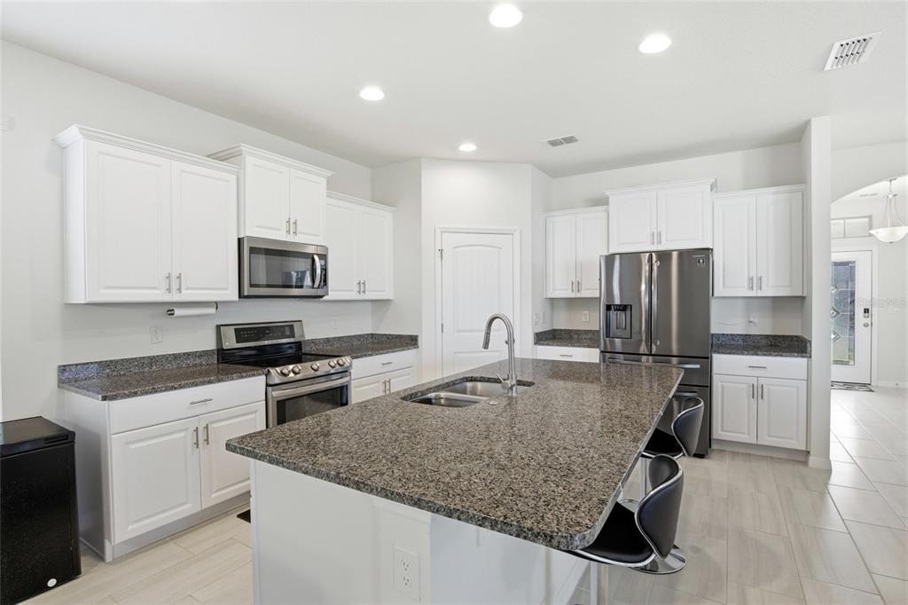 16098 Mangrove Road Winter Garden, FL 34787 - Photo 5 of 40 a kitchen with stainless steel appliances granite countertop a sink stove microwave and refrigerator