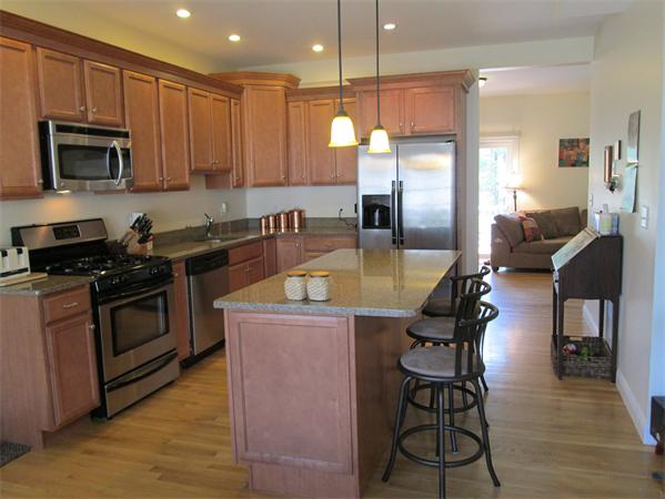 6 B Charles Ridge Road, Unit B Littleton, MA 01460 - Photo 2 of 16 a kitchen with stainless steel appliances kitchen island granite countertop a stove a sink a microwave a dining table and chairs with wooden floor