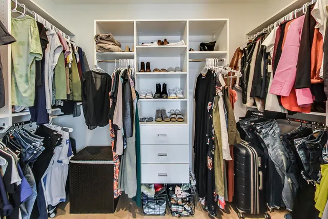 a view of walk in closet with clothes and shoes