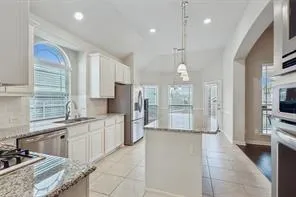 a large kitchen with stainless steel appliances kitchen island granite countertop a sink and cabinets