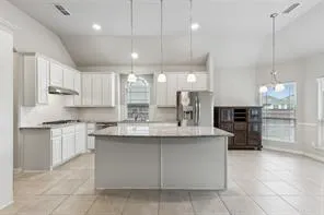a large kitchen with kitchen island a sink a stove a oven a counter space and cabinets
