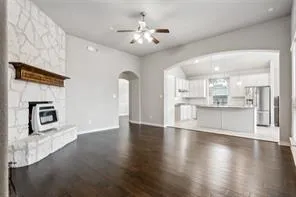 a view of an empty room with kitchen and fireplace