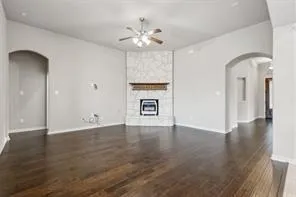 a view of an empty room with wooden floor and a ceiling fan