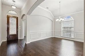 an empty room with wooden floor chandelier and windows