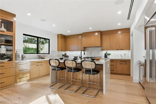 a large kitchen with white cabinets a stove a sink dishwasher a dining table and chairs with wooden floor