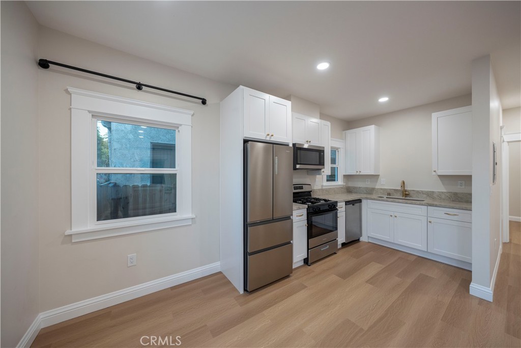 1820 2nd Street Long Beach, CA 90802 - Photo 9 of 16 a kitchen with granite countertop a refrigerator oven a sink dishwasher and white cabinets with wooden floor