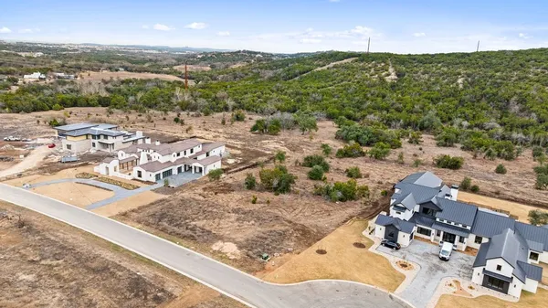 a view of a dry yard with trees in the background