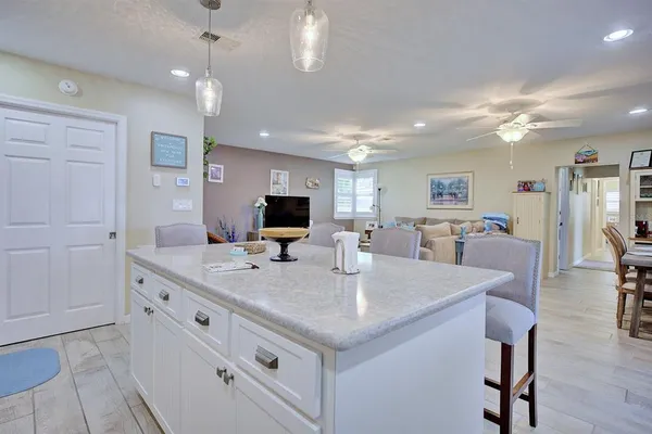 a room with stainless steel appliances kitchen island granite countertop a table chairs and a refrigerator