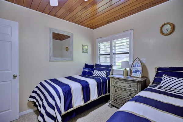 a bedroom with a bed and a lamp on dresser with a window
