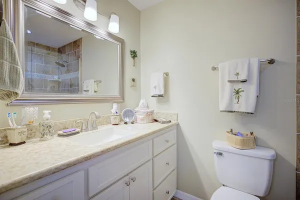 a bathroom with a granite countertop toilet sink and mirror