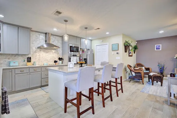 a kitchen with cabinets a sink dishwasher a island and chairs in it