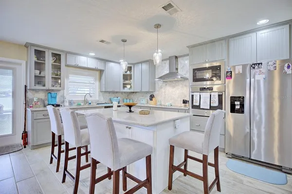 a kitchen with stainless steel appliances a table chairs refrigerator and microwave