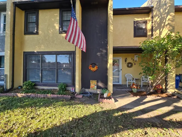 a view of a brick house with large windows and a small yard