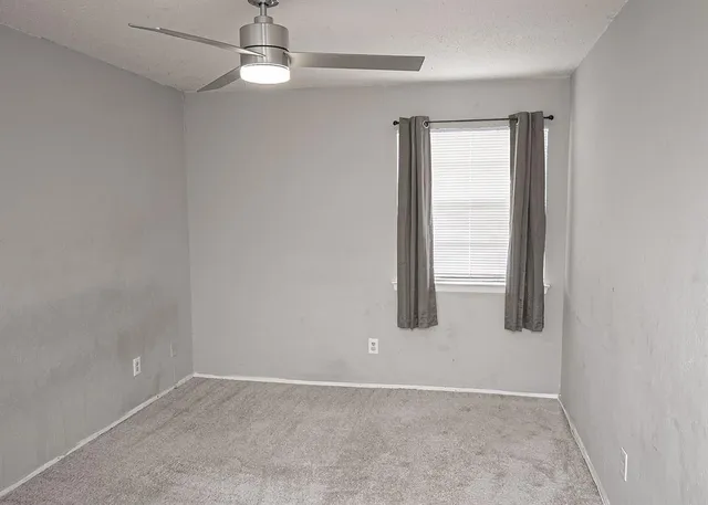 an empty room with chandelier fan