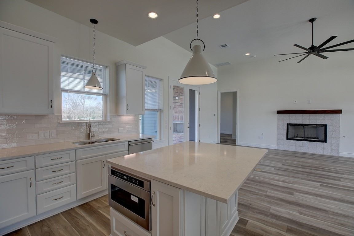 a kitchen with a sink a chandelier stainless steel appliances and cabinets