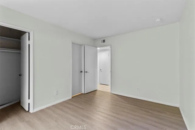 a view of an empty room with wooden floor and closet