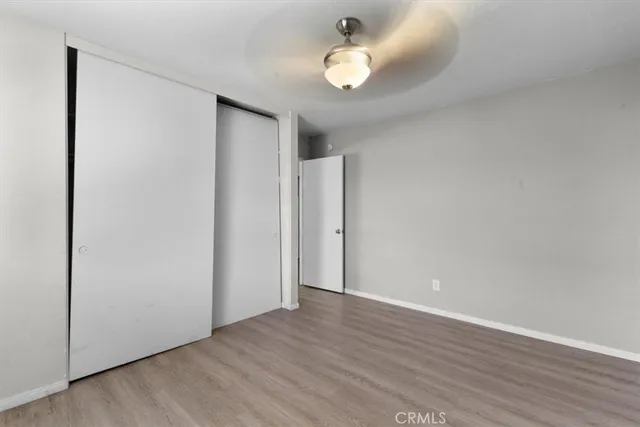 an empty room with wooden floor and ceiling fan