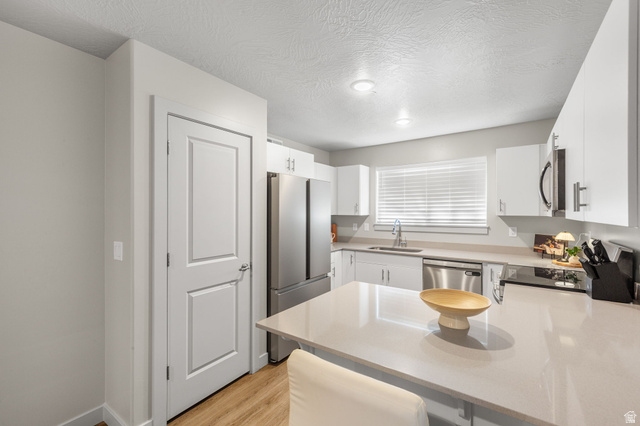 6231 Winding Way, Unit K105 Hurricane, UT 84737 - Photo 9 of 20 Kitchen featuring stainless steel appliances, white cabinets, a peninsula, light wood finished floors, and light stone countertops