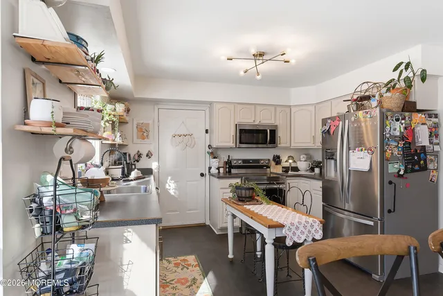 a kitchen with stainless steel appliances kitchen island granite countertop a refrigerator a stove top oven a sink dishwasher and white cabinets with wooden floor