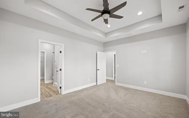 an empty room with chandelier fan and windows