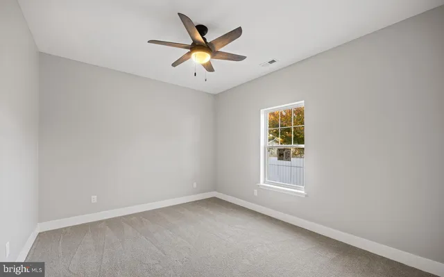 an empty room with window and ceiling fan