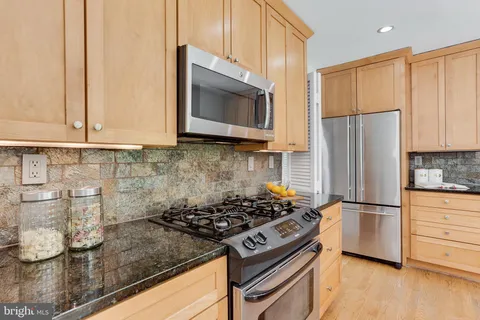 a kitchen with stainless steel appliances granite countertop a stove a refrigerator and a microwave