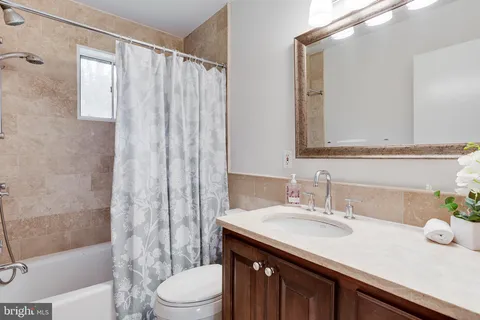 a bathroom with a granite countertop sink a toilet a mirror and shower