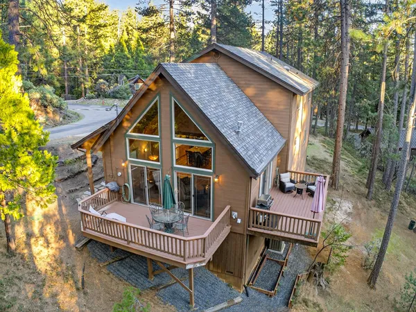 an aerial view of a house with yard and trees in the background