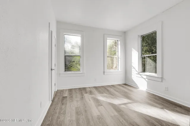 an empty room with wooden floor and windows