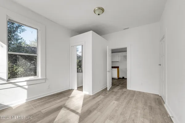 a view of an empty room with wooden floor and a window