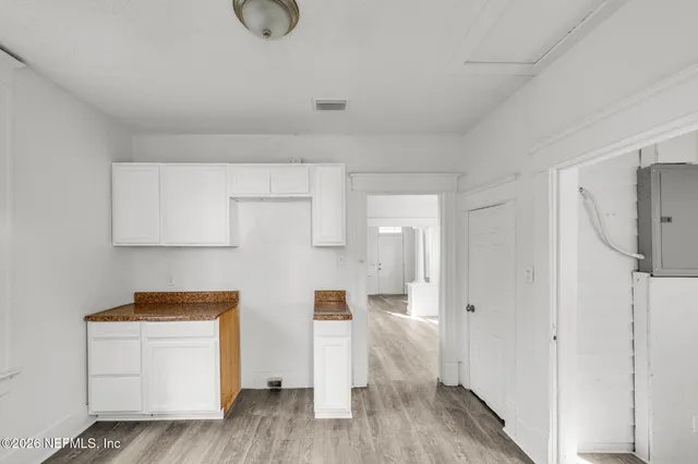 a view of kitchen with white wooden cabinets