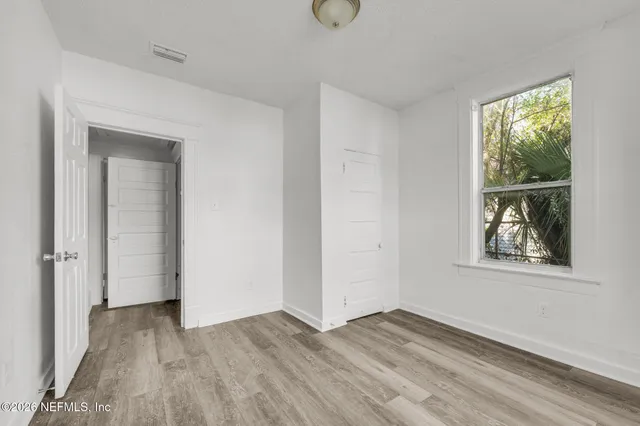 an empty room with wooden floor and windows