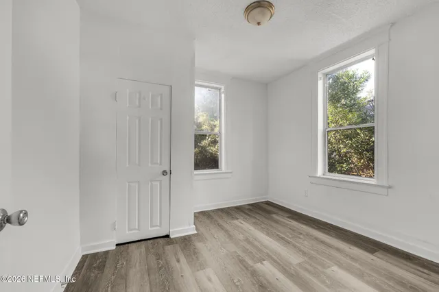 an empty room with wooden floor and windows